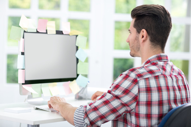 Man looking at a monitor with sticky note on it - Foto, Imagen