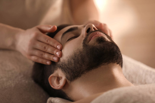 Young man receiving facial massage in beauty salon, closeup - Foto, imagen
