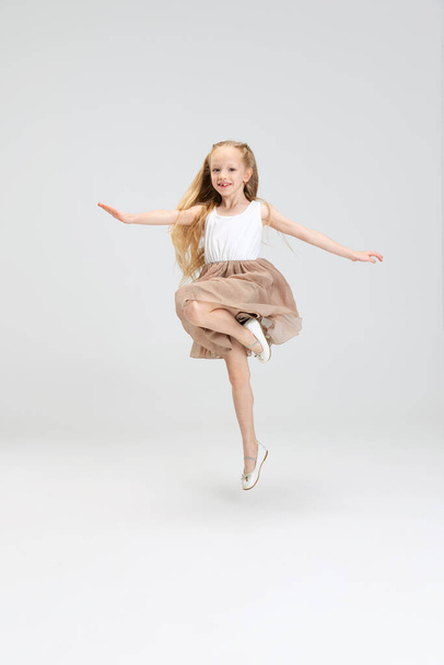 Beautiful little girl in modern stylish dress posing isolated on white studio background. Happy childhood concept. - Foto, Imagem