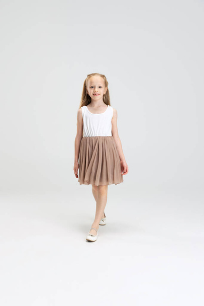 Beautiful little girl in modern stylish dress posing isolated on white studio background. Happy childhood concept. - Фото, зображення