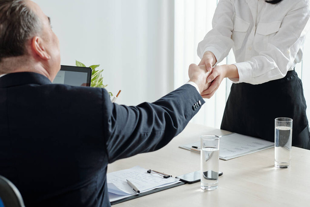 Close-up imago van vrouwelijke sollicitant schudden hand van bedrijfsleider voor belangrijk sollicitatiegesprek - Foto, afbeelding