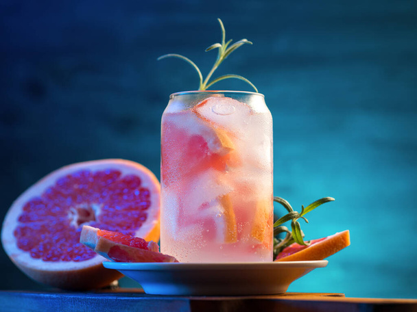 Холодний алкогольний коктейль з джином, грейпфрутом, розмарином та содовою. Шматочки грейпфрута, барвистий синій фон і стильне скло
 - Фото, зображення