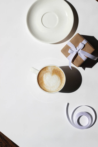 Cappuccino with Latte Art on White Background with Wrapped Gift Box. Holidays Celebration.  - Valokuva, kuva