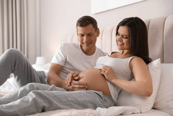 Young pregnant woman with her husband in bedroom - Foto, afbeelding
