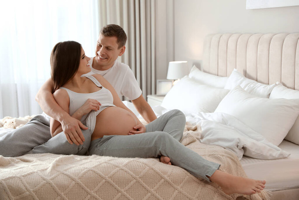 Young pregnant woman with her husband in bedroom - Foto, Bild