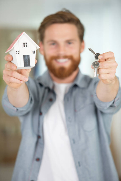 handsome man holding model house and keys in hands - Foto, immagini