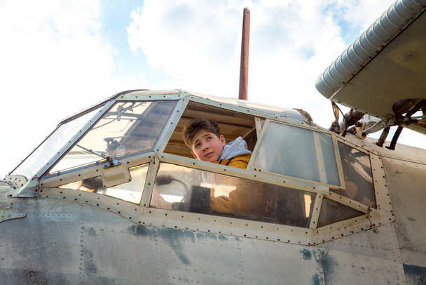 Un giovane a bordo di un vecchio aereo sovietico abbandonato. Il tipo guarda fuori dalla finestra. - Foto, immagini