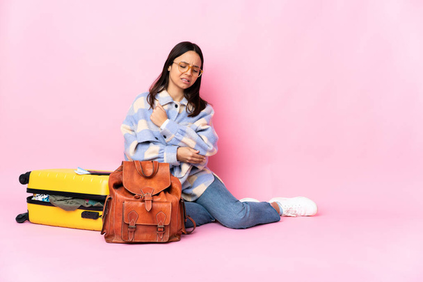Mulher viajante com uma mala sentada no chão com dor no cotovelo - Foto, Imagem