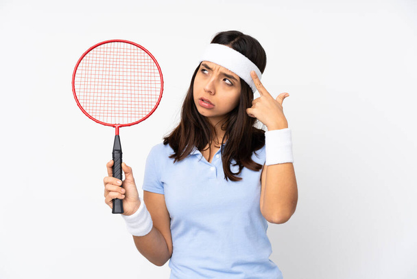 Genç badmintoncu kadın izole edilmiş beyaz arka planda deliliğin jestini yapıyor parmağını kafaya koyuyor. - Fotoğraf, Görsel