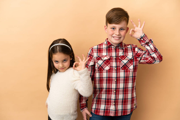 Little Caucasian brother and sister isolated on beige background - Photo, Image