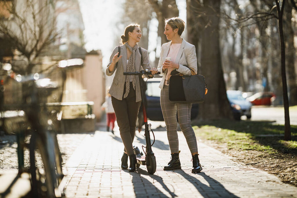 Dwie odnoszące sukcesy biznesmenki rozmawiające podczas spaceru po mieście. - Zdjęcie, obraz