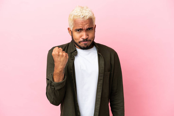 Young Colombian handsome man isolated on pink background with unhappy expression - Foto, afbeelding