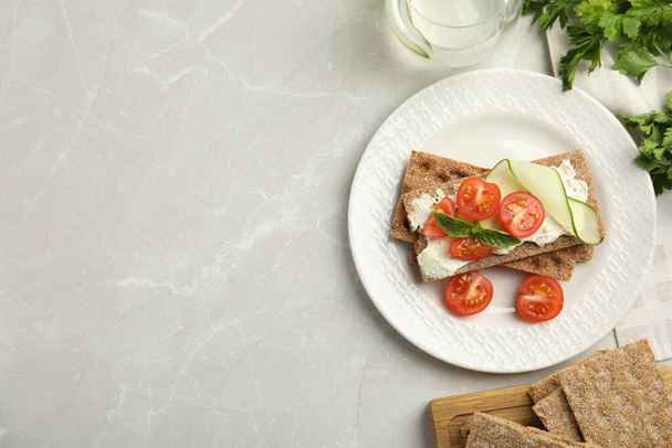 Fresh rye crispbreads with cream cheese and vegetables on light grey marble table, flat lay. Space for text - Valokuva, kuva