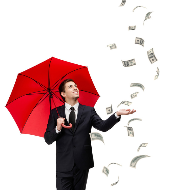 Man with red umbrella looks at falling money - Фото, изображение