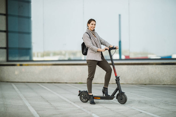 A young businesswoman with an electric push scooter going to work. - Photo, Image