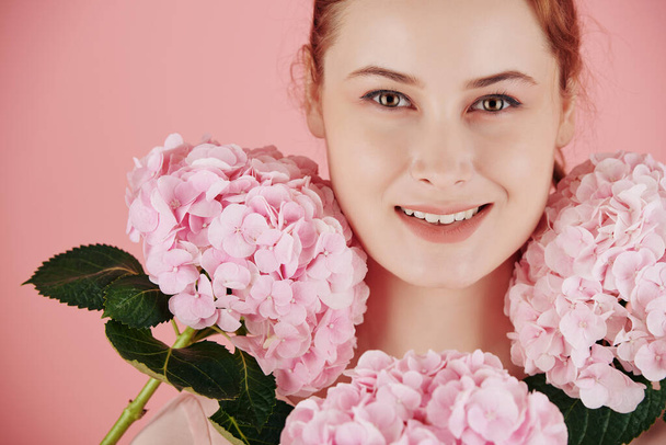 Kaunis kukkiva vaaleanpunainen hortensia kukkia ympärillä kasvot kaunis nuori hymyilevä nainen - Valokuva, kuva
