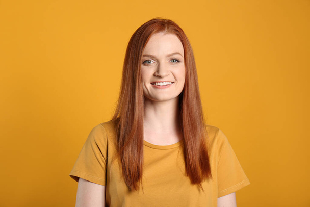 Candid portrait of happy young woman with charming smile and gorgeous red hair on yellow background - Φωτογραφία, εικόνα