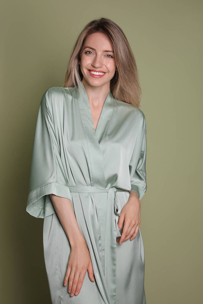Pretty young woman in beautiful light green silk robe on olive background - Valokuva, kuva
