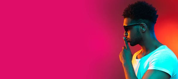 Портрет молодого африканського чоловіка в сонцезахисних окулярах в студії на яскраво-рожевому неоновому фоні
. - Фото, зображення