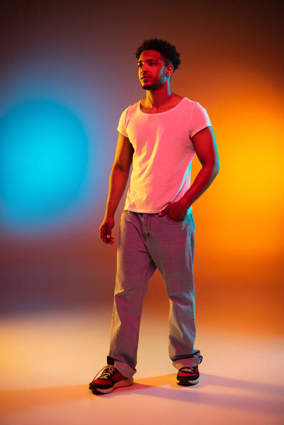Retrato de un joven africano en el estudio. Modelo masculino de alta moda en luces de neón brillantes de colores. Concepto de diseño artístico. - Foto, Imagen