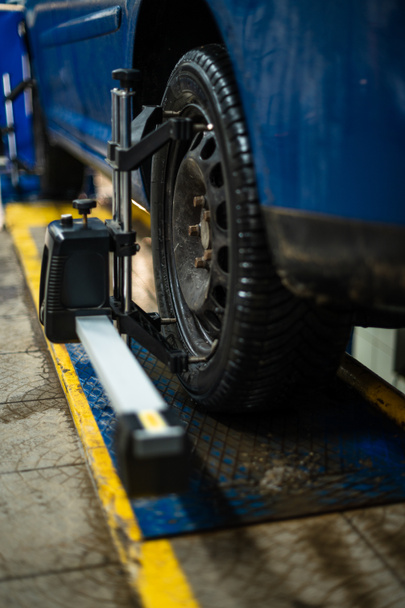 Garajdaki tekerleklerin otomatik hizasını, garajı ve tamirci için aletleri geçen bir düzleştirici tarafından sıkıştırılmış lastiğin yakın çekimi. yeni - Fotoğraf, Görsel