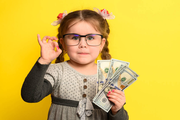 Niet-kind geld besparen in handen van kinderen, gele achtergrond en geld met baby. nieuw - Foto, afbeelding