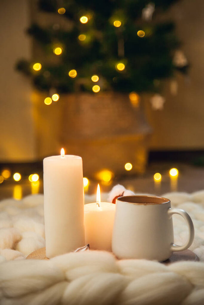 Cup of cappuccino, cookies, and candles on the background of blanket of thick yarn. The atmosphere of homeliness and comfort. - Photo, Image