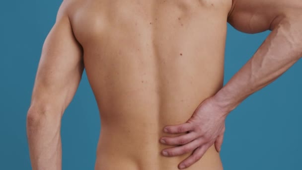 Nahaufnahme eines bis zur Unkenntlichkeit muskulösen Mannes, der seinen schmerzhaften rechten Unterschenkel berührt und an Nieren- oder Lendenschmerzen leidet - Filmmaterial, Video