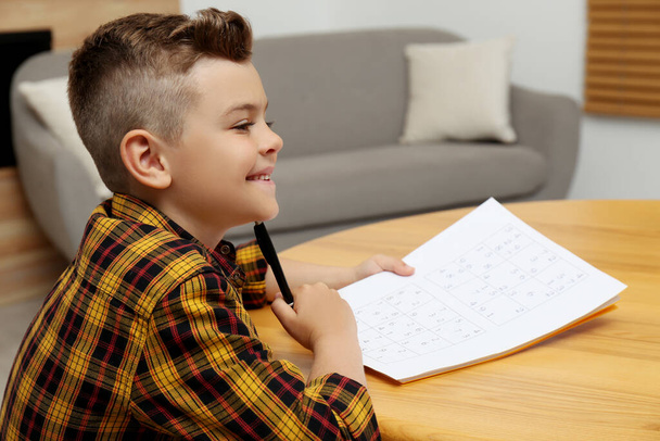 Little boy solving sudoku puzzle at table indoors - Foto, immagini
