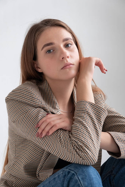 jonge aantrekkelijke Kaukasische vrouw met lang bruin haar in pak jas in studio - Foto, afbeelding