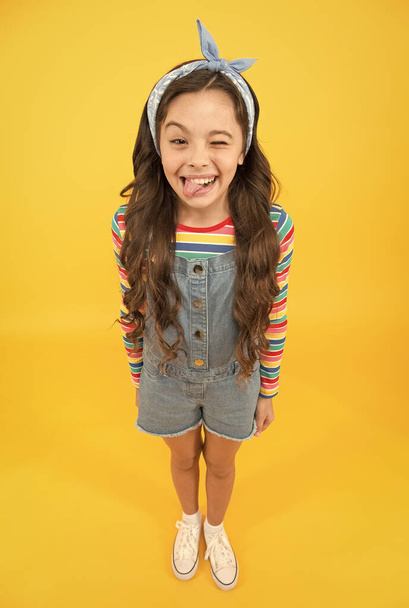 Fun lifestyle little girl long hair denim overalls, cheerful grimace concept - Photo, image