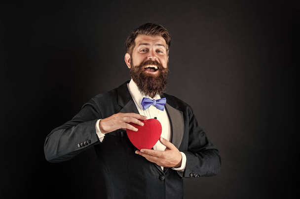 handsome man in tuxedo holding love gift of heart for valentines day, valentine - Foto, afbeelding