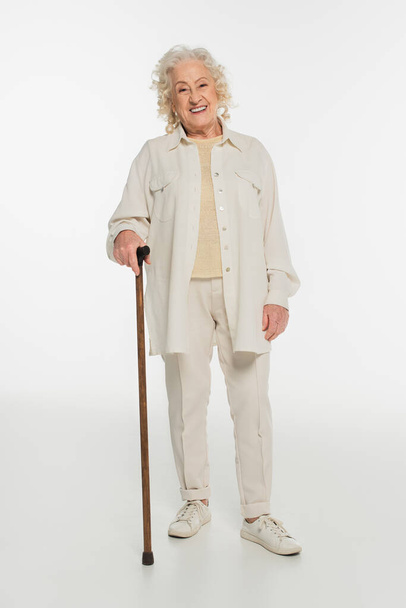 mosolygós idős nő alkalmi ruhák álló sétapálca fehér - Fotó, kép