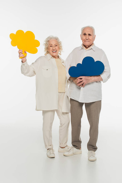 glimlachend ouder paar met gele gedachte bubbels en kijken naar de camera op wit - Foto, afbeelding