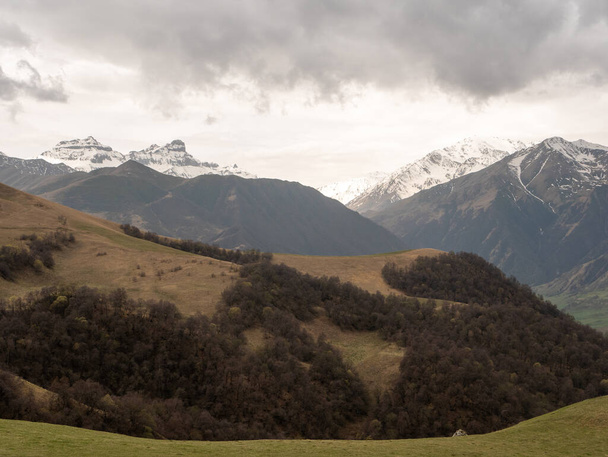 Aktoprak to przełęcz, znana od czasów starożytnych, łącząca wąwozy Baksan i Chegem. Ładny widok na zielone wzgórza pokryte roślinnością i wysokie góry ze śnieżnymi szczytami. Kabardino-Bałkaria, Rosja - Zdjęcie, obraz