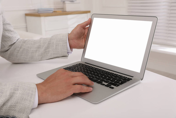 Бізнесмен з сучасним ноутбуком на білому столі в приміщенні, крупним планом. Простір для дизайну
 - Фото, зображення