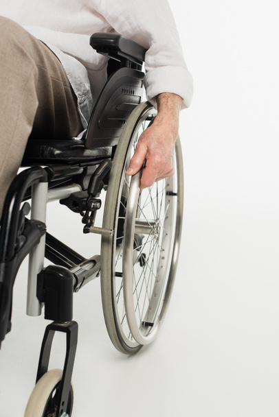 partial view of elderly man sitting in wheelchair on white - Фото, зображення