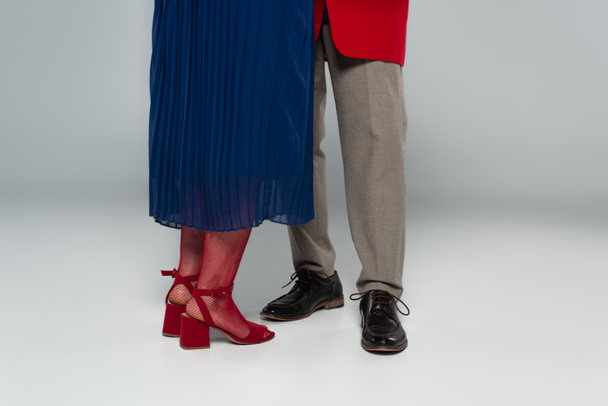 částečný pohled na mužské a ženské nohy ve stylových šatech tančících na šedi - Fotografie, Obrázek