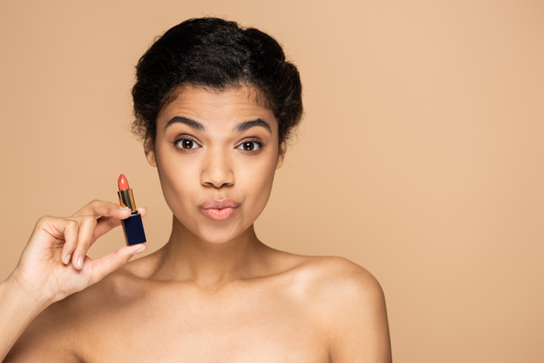 afro-amerikai nő duzzogó ajkak és a gazdaság rúzs izolált bézs  - Fotó, kép
