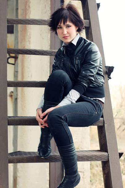Беззаботная девушка, одетая в черное на металлической лестнице
 - Фото, изображение