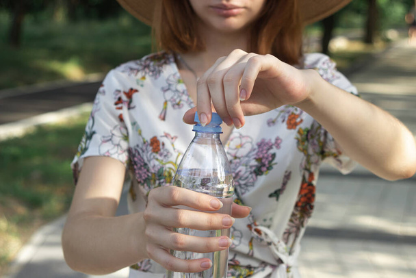 Tyttö avaa pullollisen vettä. Puhdasta juomavettä muovipullossa. Vesipullon avaaminen lähikuva - Valokuva, kuva