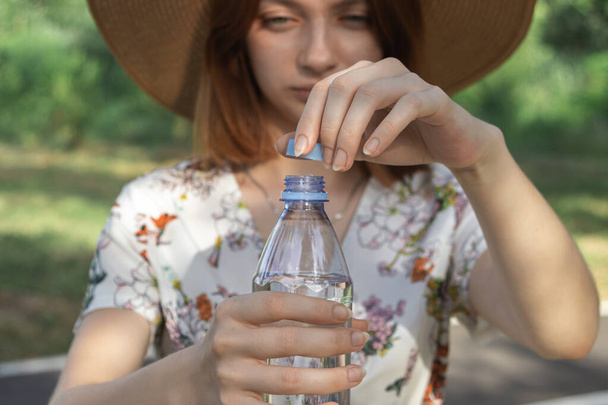 La ragazza apre una bottiglia d'acqua. Acqua potabile pura in una bottiglia di plastica. Apertura bottiglia d'acqua primo piano - Foto, immagini