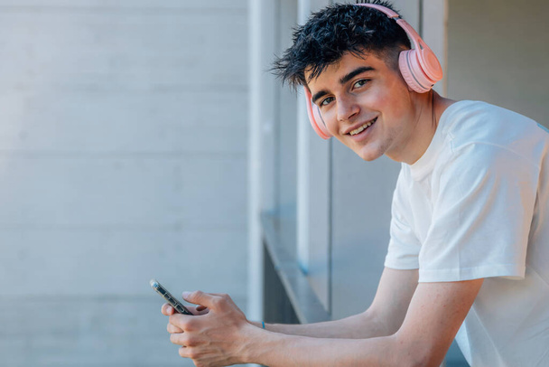 adolescente con teléfono móvil y auriculares en el balcón - Foto, Imagen