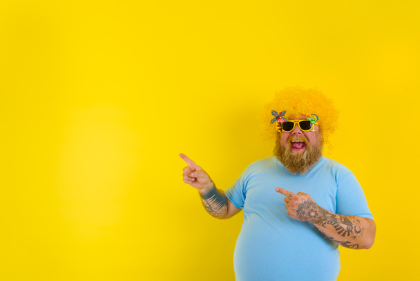 Fat man with wig in head and sunglasses indicates with hands something - Foto, Imagen