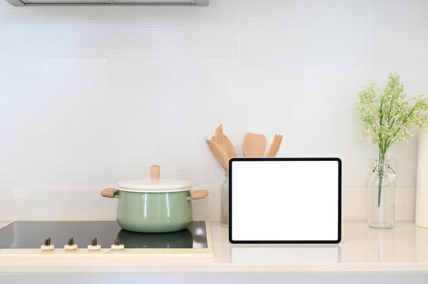 Κουζινικά σκεύη και tablet με λευκή οθόνη στο σύγχρονο πάγκο κουζίνας. - Φωτογραφία, εικόνα