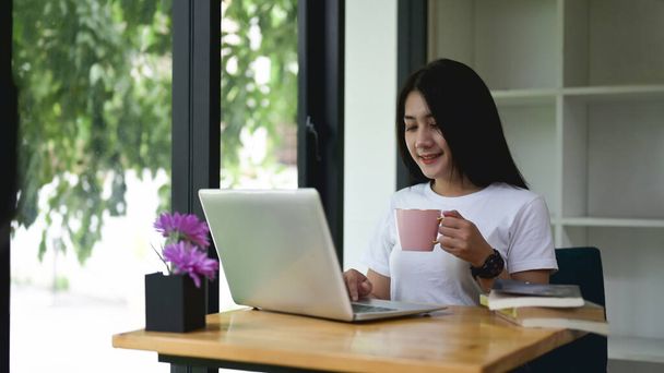 Jovem empreendedor trabalha com laptop enquanto toma café no escritório. - Foto, Imagem