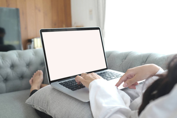 Крупним планом молода жінка використовує ноутбук на дивані після пробудження на вихідних вранці
. - Фото, зображення