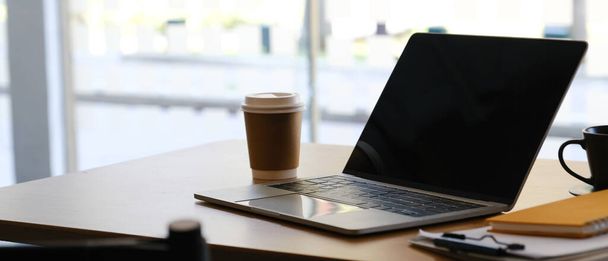 Комп'ютер ноутбука на робочому місці з паперовою чашкою кави, ноутбуком
. - Фото, зображення