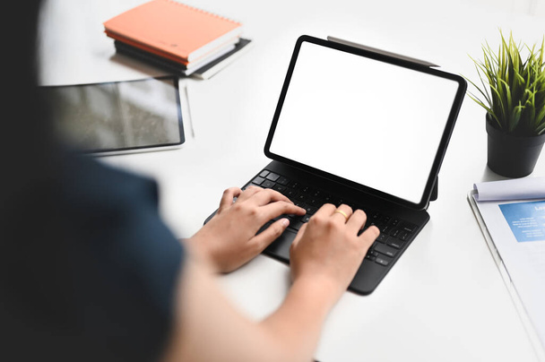 Uma imagem de close-up de uma mulher está usando um tablet de computador na mesa de trabalho branca. - Foto, Imagem