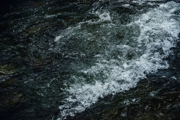 Nature background of dark water stream of mountain river with rapids. Full frame of sea surf. Natural textured backdrop of ocean surf. Texture of tide close-up. Dark water surface of mountain creek. - Fotó, kép